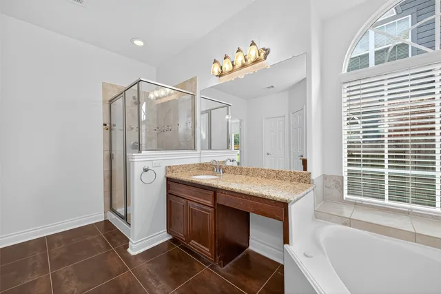 a bathroom with a granite countertop sink a large mirror and a bathtub