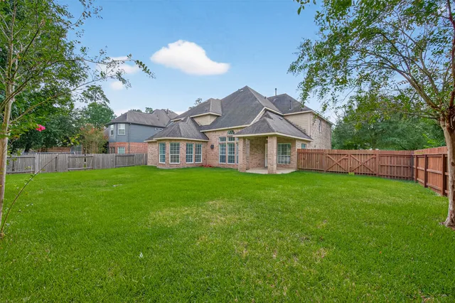 a view of a big house with a big yard and potted plants and a large tree