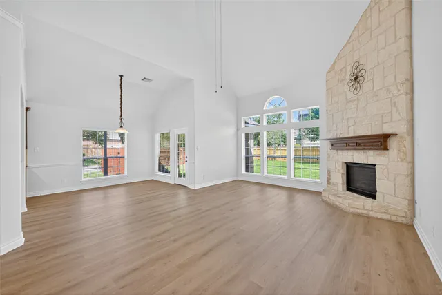 a view of an empty room with wooden floor fireplace and a window