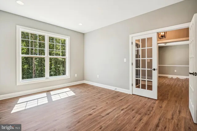 a view of an empty room with wooden floor and windows