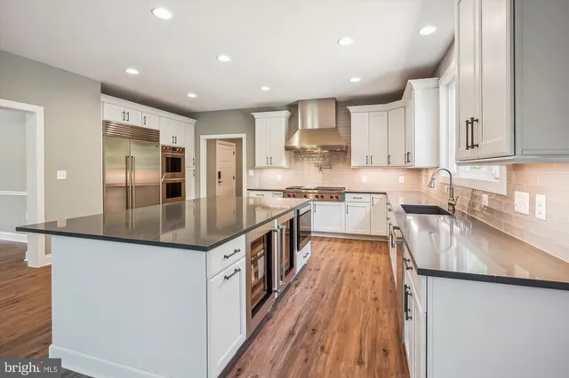 a kitchen with stainless steel appliances granite countertop a refrigerator a stove and a wooden floors