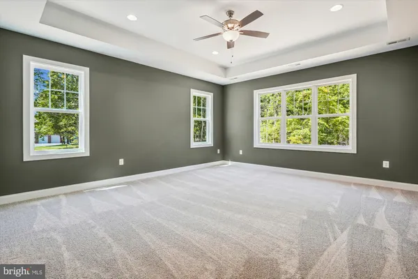 an empty room with a ceiling fan and windows