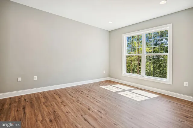 a view of an empty room with wooden floor and windows