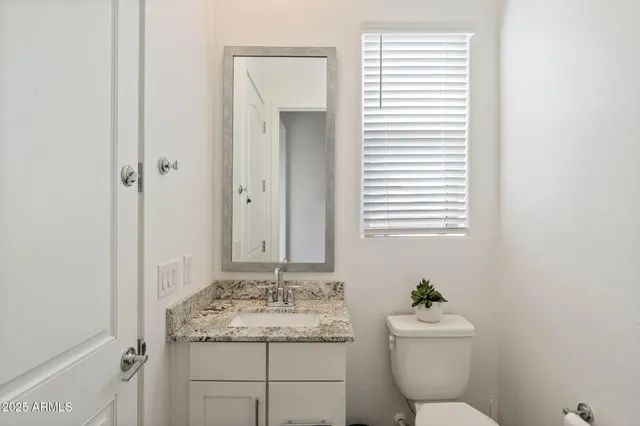 a bathroom with a granite countertop sink toilet and mirror