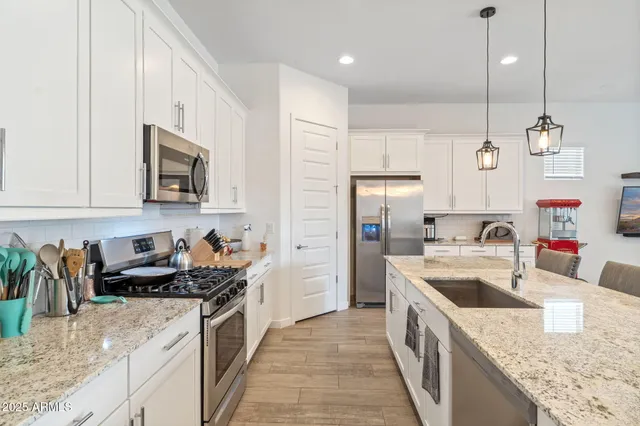 a kitchen with stainless steel appliances granite countertop a sink a stove and a refrigerator