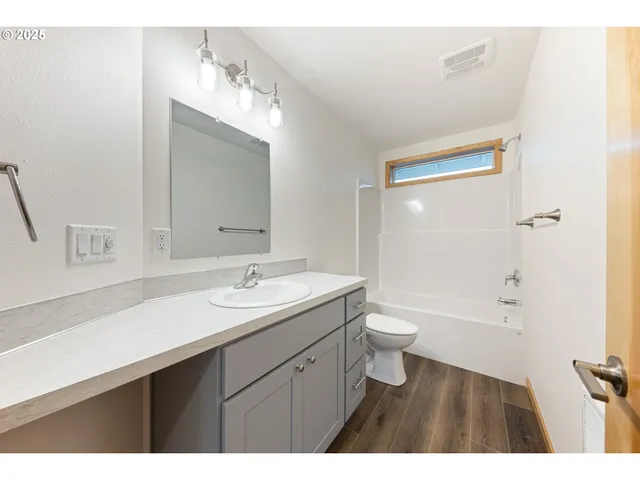 a bathroom with a granite countertop sink toilet a large mirror a bathtub and shower