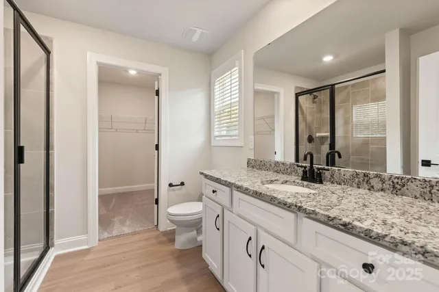 a bathroom with a granite countertop toilet a sink and a shower