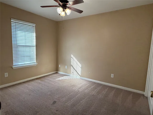 an empty room with a window and a fan