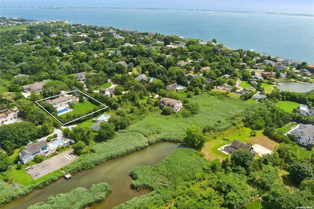 an aerial view of a residential houses with outdoor space and trees all around