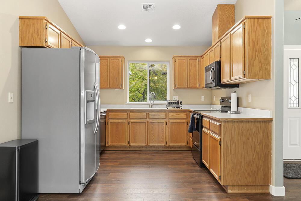 520 Stewart Road Grants Pass, OR 97526 - Photo 8 of 47 a kitchen with stainless steel appliances granite countertop a refrigerator a sink dishwasher and wooden cabinets with wooden floor