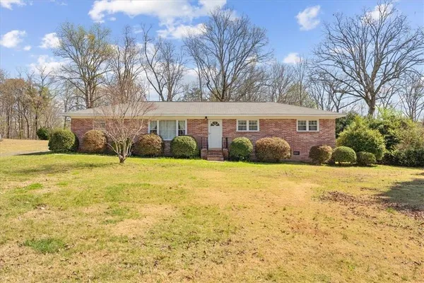 a front view of house with yard and trees in the background