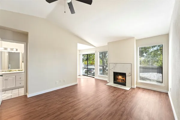 an empty room with wooden floor fireplace and windows