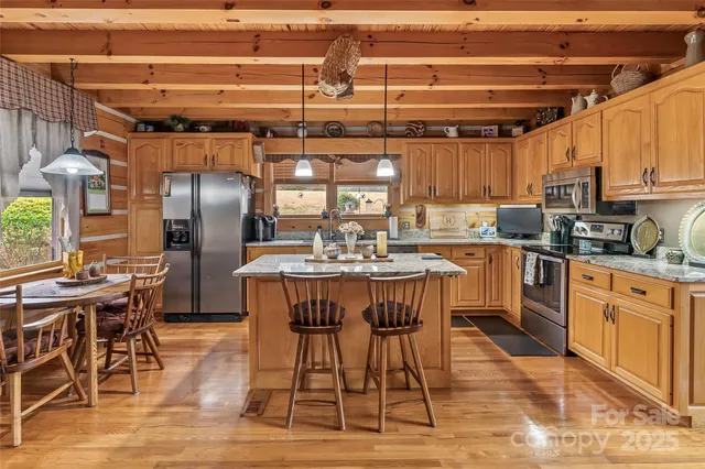 a kitchen with stainless steel appliances granite countertop a dining table chairs refrigerator and sink