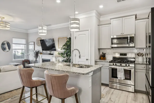 a kitchen with stainless steel appliances kitchen island granite countertop a stove a sink a microwave a dining table and chairs