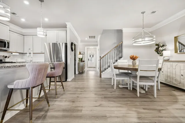 a dining room with wooden floor a chandelier a wooden table and chairs
