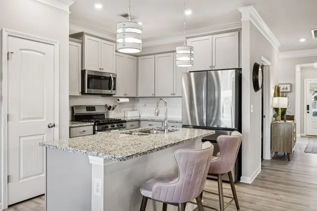 a kitchen with stainless steel appliances granite countertop a refrigerator a stove a sink a dining table and chairs with wooden floor