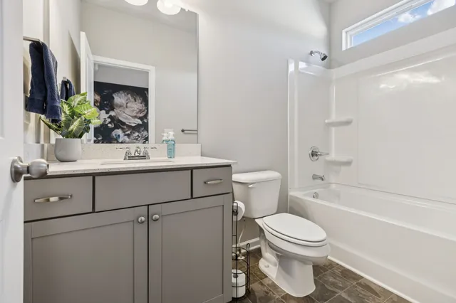 a white bath tub sitting next to a white toilet and vanity