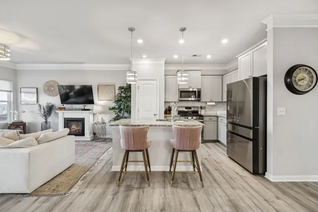 a kitchen with stainless steel appliances a refrigerator a stove top oven a sink dishwasher a dining table and chairs with wooden floor