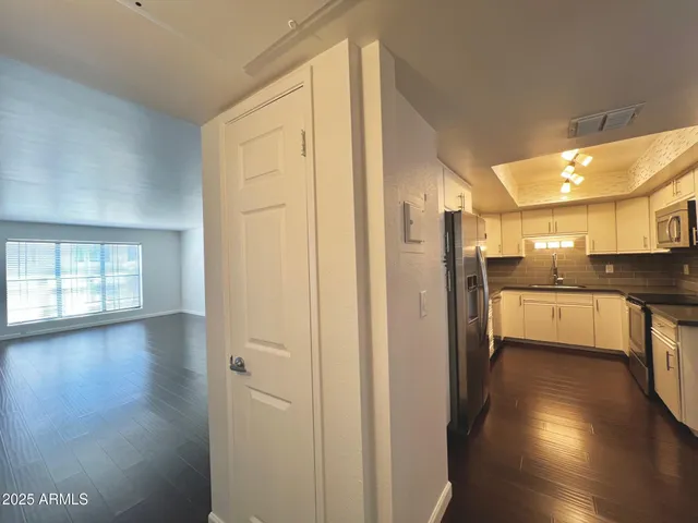 a view of a hallway with wooden floor and a kitchen