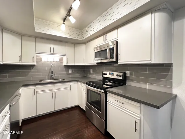 a kitchen with stainless steel appliances granite countertop a sink a stove a microwave and cabinets