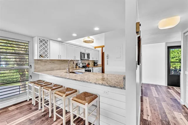 a kitchen with granite countertop a stove a sink and a refrigerator