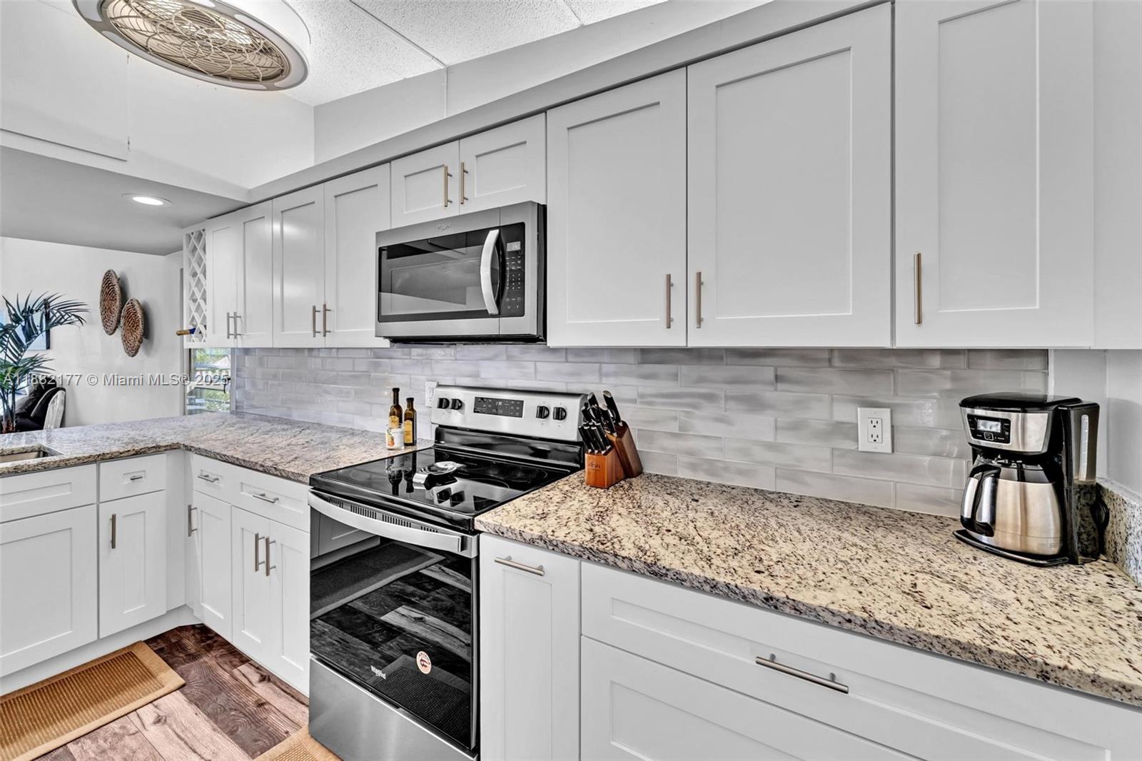 1456 Northeast Ocean Boulevard, Unit 7204 Stuart, FL 34996 - Photo 27 of 64 a kitchen with granite countertop a stove sink and cabinets