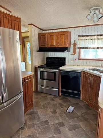 a kitchen with stainless steel appliances granite countertop a refrigerator a stove a sink and dishwasher