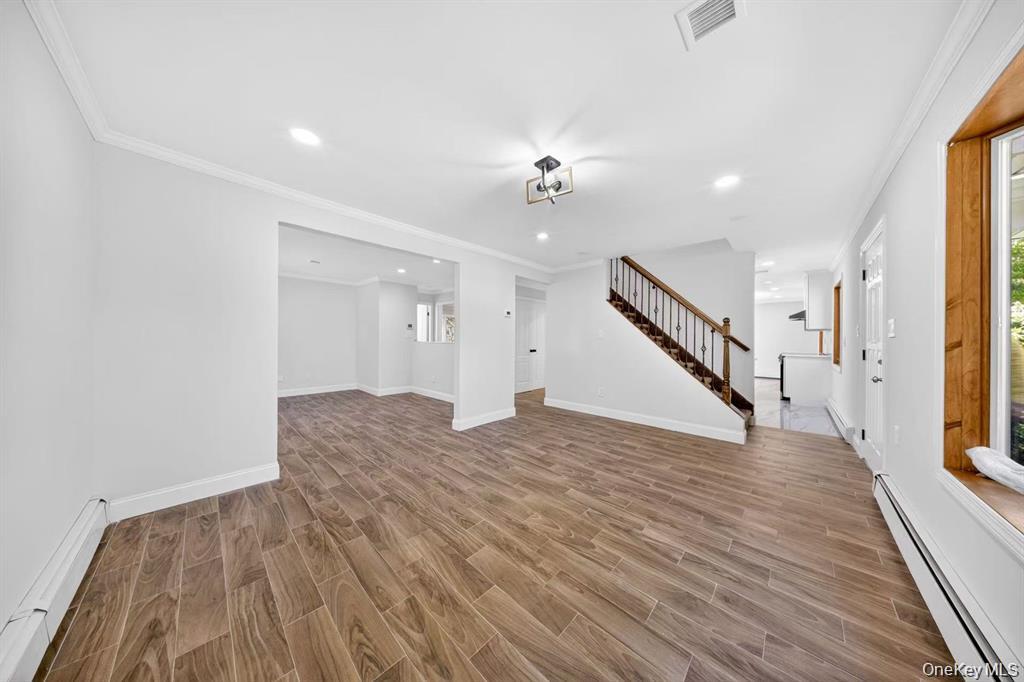 Wood-finish flooring throughout, recessed lighting, crown molding, and a wood-stained window frame