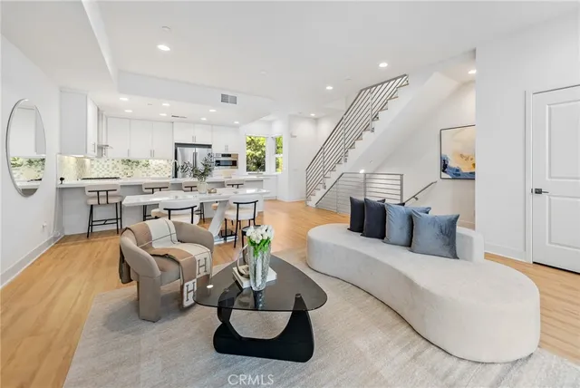 a living room with furniture kitchen view and a chandelier