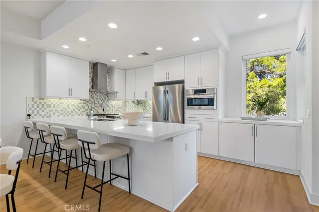 a kitchen with stainless steel appliances granite countertop a stove a refrigerator a microwave oven a dining table and chairs with wooden floor