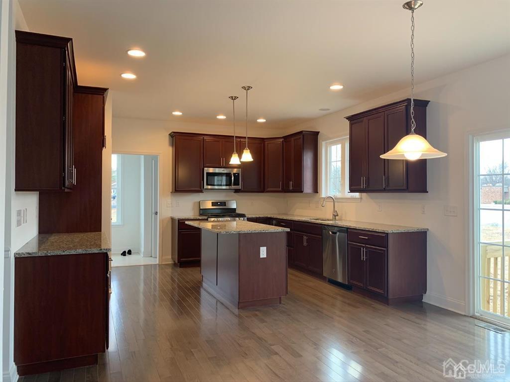 19 May Road East Brunswick, NJ 08816 - Photo 4 of 7 a large kitchen with stainless steel appliances granite countertop a refrigerator a sink dishwasher a stove and a dining table with wooden floor