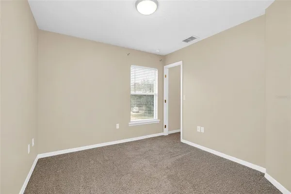 a view of an empty room with a window and closet area