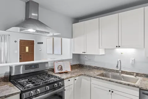 a kitchen with granite countertop stainless steel appliances sink stove and cabinets