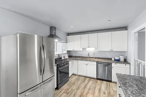 a kitchen with stainless steel appliances granite countertop a stove top oven a refrigerator and white cabinets
