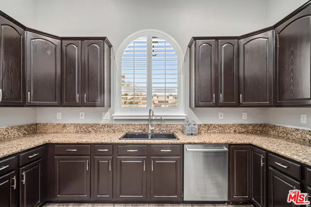 a kitchen with granite countertop a sink stainless steel appliances and cabinets