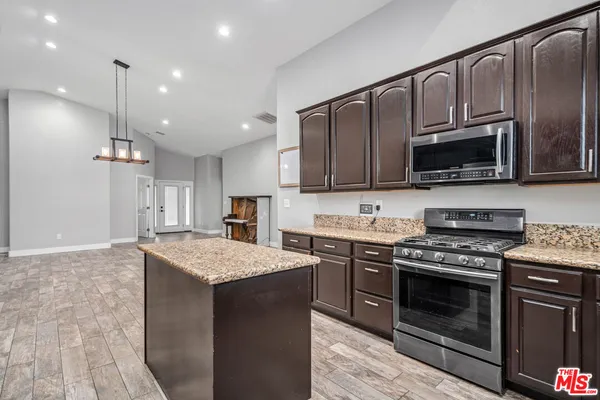 a kitchen with granite countertop wooden cabinets stainless steel appliances and a sink