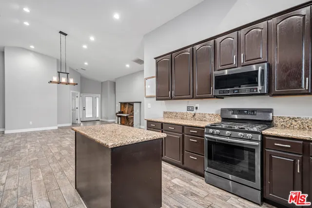 a kitchen with granite countertop wooden cabinets stainless steel appliances and a sink