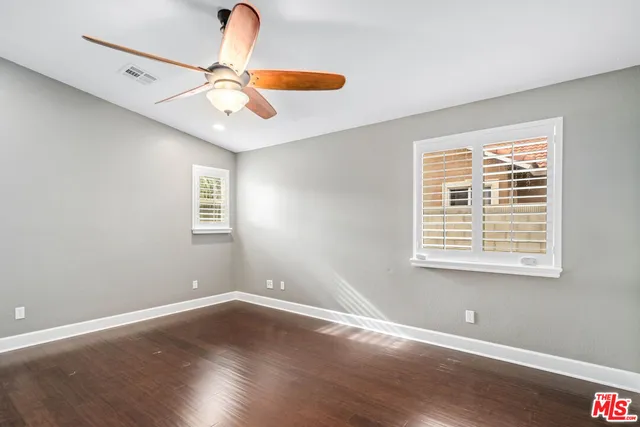 a view of empty room with wooden floor and fan
