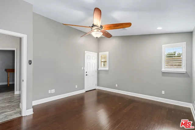 an empty room with wooden floor chandelier fan and windows