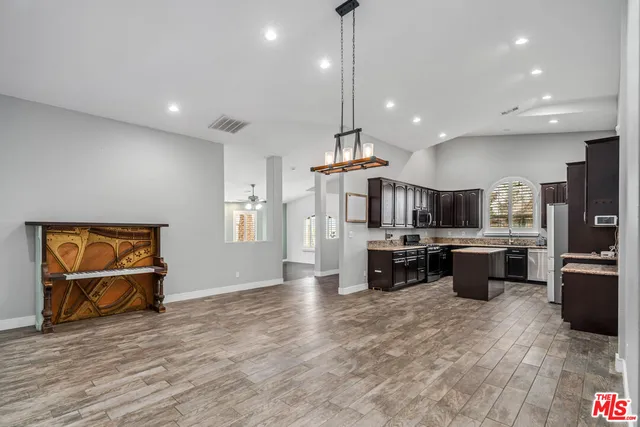 a kitchen with kitchen island a stove a refrigerator a sink dishwasher a oven and a dining table with wooden floor