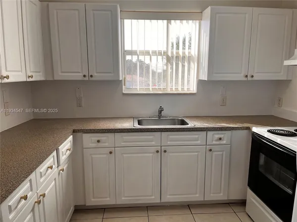 a kitchen with granite countertop white cabinets and sink