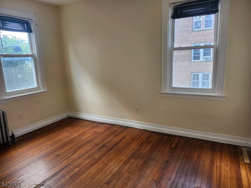 313 Leslie Street Newark, NJ 07112 - Photo 4 of 7 an empty room with wooden floor and windows