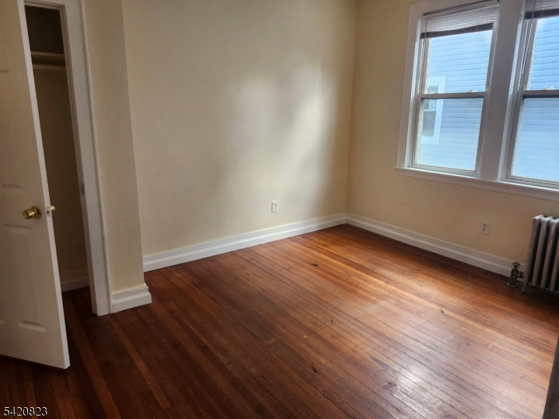 313 Leslie Street Newark, NJ 07112 - Photo 5 of 7 an empty room with wooden floor and windows