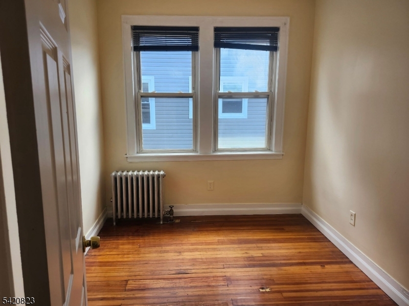 313 Leslie Street Newark, NJ 07112 - Photo 7 of 7 a view of an empty room with wooden floor and a window