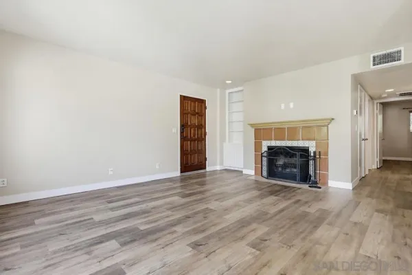 an empty room with wooden floor fireplace and windows