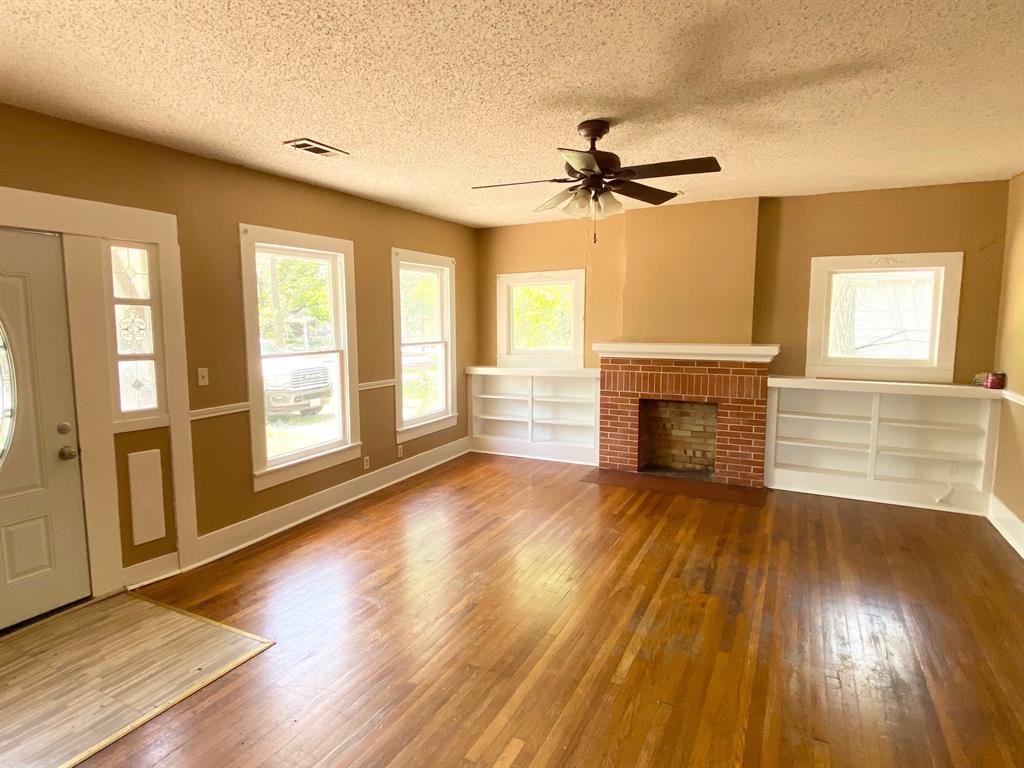 106 West Decatur Street Ennis, TX 75119 - Photo 10 of 17 an empty room with wooden floor fireplace and windows