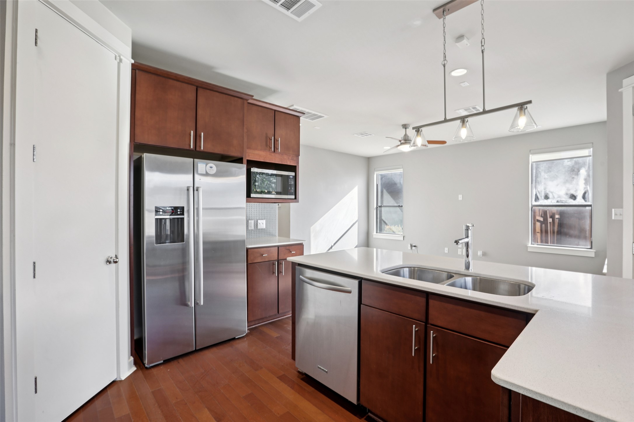 1123 Blair Way Austin, TX 78704 - Photo 9 of 30 Kitchen with appliances with stainless steel finishes, dark wood-style flooring, ceiling fan, hanging light fixtures, and light stone countertops