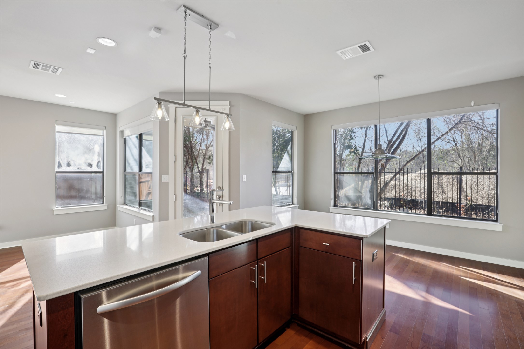 1123 Blair Way Austin, TX 78704 - Photo 11 of 30 Kitchen featuring stainless steel dishwasher, dark brown cabinets, decorative light fixtures, a center island with sink, and dark wood finished floors