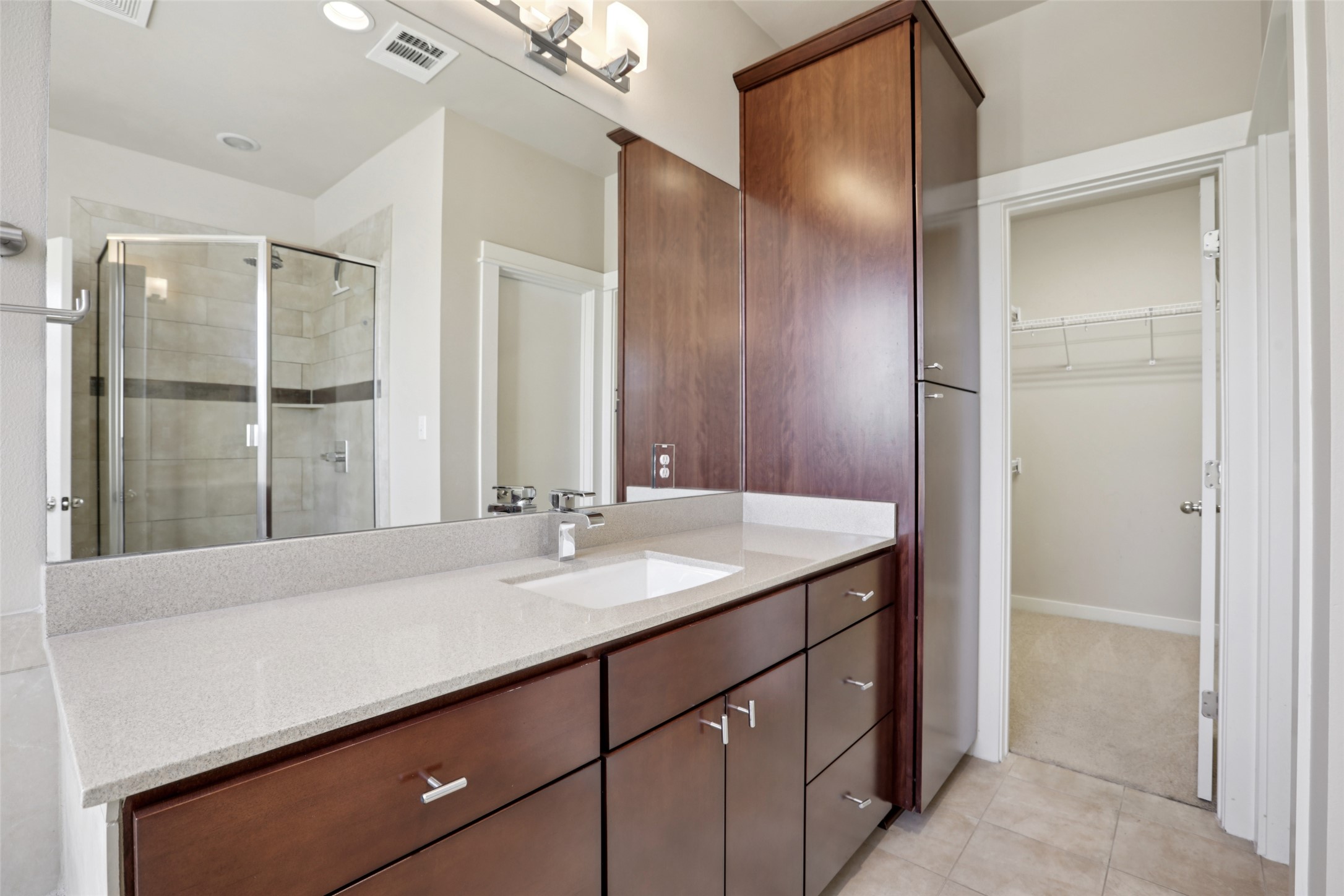 1123 Blair Way Austin, TX 78704 - Photo 22 of 30 Bathroom with vanity, a shower stall, a walk in closet, light colored carpet, and light tile patterned floors