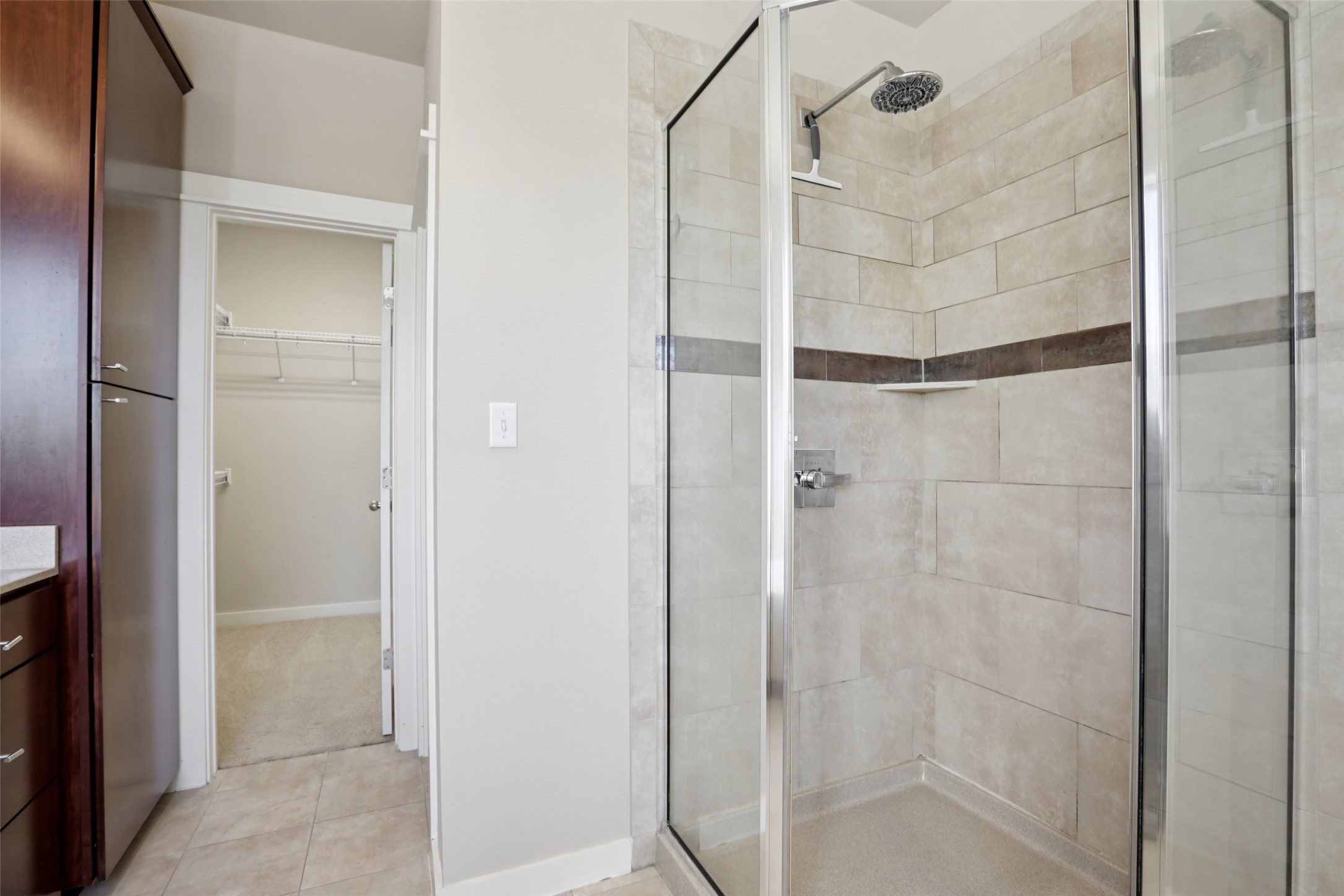 1123 Blair Way Austin, TX 78704 - Photo 23 of 30 Full bath with vanity, a walk in closet, a shower stall, and light tile patterned floors